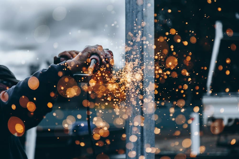 A metalworker grinding steel, with sparks illuminating the workshop